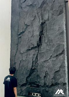 a man is standing in front of a large rock wall that looks like it has been carved