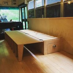 a bed sitting on top of a wooden floor next to a window with lots of windows