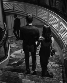 two people walking down an escalator in black and white, one holding the hand of the other's hand