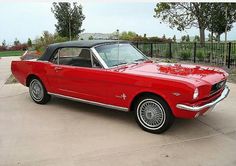 an old red mustang convertible parked in a driveway