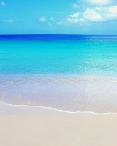 an empty beach with blue water and white sand