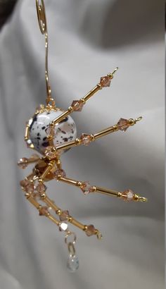 a close up of a brooch on a white cloth with gold chains and beads