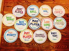 many different types of badges on a wooden surface with words written in them and the names of each team