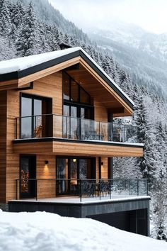 a large wooden house in the middle of snow covered mountains with trees on either side