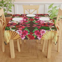 the table cloth is decorated with flowers and fan shaped plates on it, along with four wooden chairs