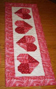 a quilted table runner with hearts on it