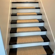 a set of stairs with black and white carpet on the bottom, and beige carpet on the bottom