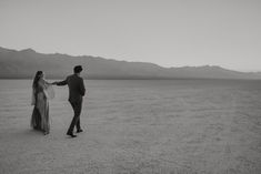 a man and woman holding hands in the desert