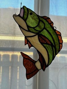 a stained glass fish hanging from a window