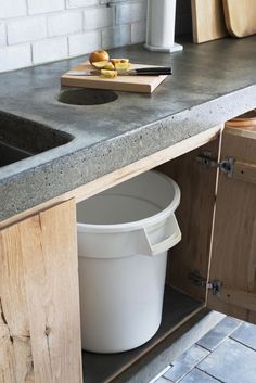 a white bucket sitting on top of a kitchen counter next to a wooden cutting board