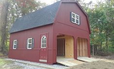 a small red barn with windows and doors