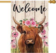 a cow with flowers on its head is standing in front of a wooden sign that says welcome