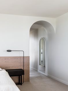 a bedroom with white walls and an arched doorway leading to a bed room that has a bench on the floor