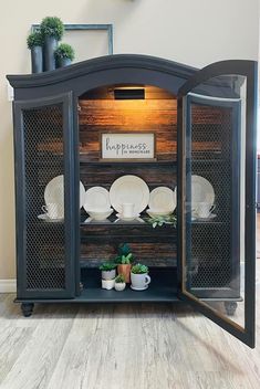 an open cabinet with plates and plants in it