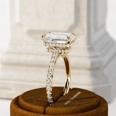 a diamond ring on top of a wooden stand in front of a white marble column