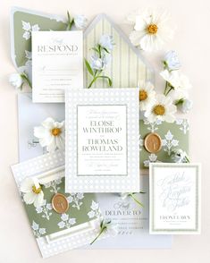 the wedding stationery is laid out on top of each other, with white flowers and greenery