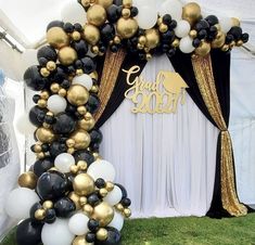 a balloon arch with black, white and gold balloons