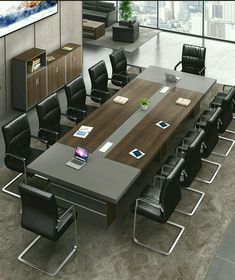 a large conference table with black leather chairs and an open laptop computer on the desk