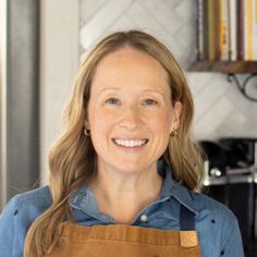 a smiling woman wearing an apron in the kitchen