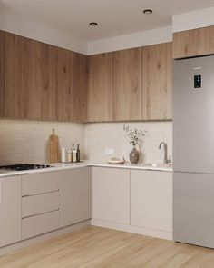 a kitchen with white cabinets and wood flooring is pictured in this image, there is a stainless steel refrigerator next to the sink