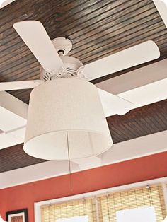 a ceiling fan with a white shade hanging from it's center piece in a living room