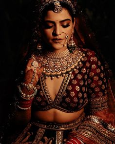 a woman in a red and gold bridal outfit with her hands on her chest