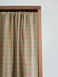 a window with a curtain hanging on it's side in front of a white wall