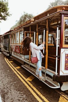 a woman climbing onto the side of a trolley car