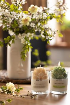 two candles sitting on top of a table next to a vase with flowers in it