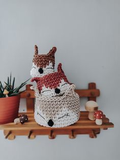 two crocheted animals sitting on top of a wooden shelf next to a potted plant