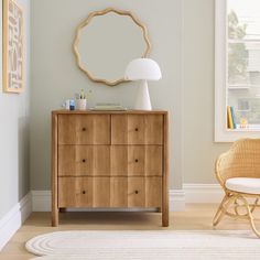 a room with a dresser, chair and mirror on the wall next to a window