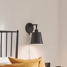 a bed with two lamps on either side of the headboard and one lamp is turned on