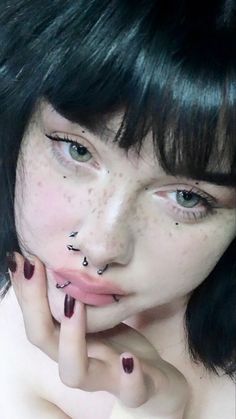 a close up of a person with freckles on her face and hand near her mouth