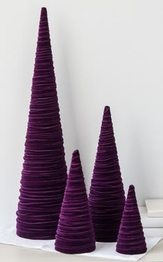 three purple cones are stacked on top of each other in front of a white wall