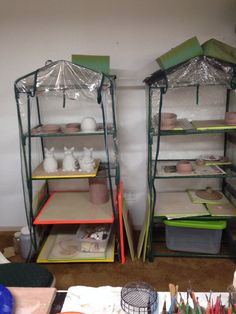 two shelving units with plastic coverings on the top and bottom shelves in an art studio