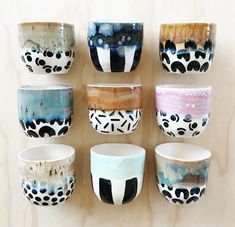 there are many bowls on the wall with different designs and colors in them, all hand painted