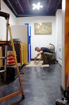 a man is laying on the floor in a room with ladders and other items