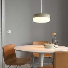 a white table with four chairs and a bowl on it in front of a gray wall