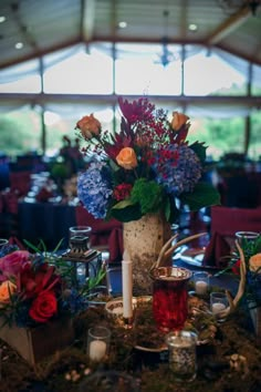 a vase filled with flowers sitting on top of a table covered in greenery and candles