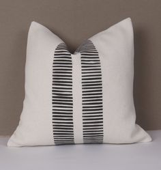 a black and white striped pillow sitting on top of a bed next to a wall