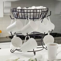 cups are stacked in a wire basket on the kitchen counter next to a coffee cup holder