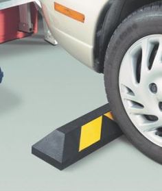 a car is parked next to a yellow and black caution line on the ground with another vehicle in the background