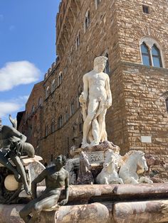 a fountain with statues in front of a brick building