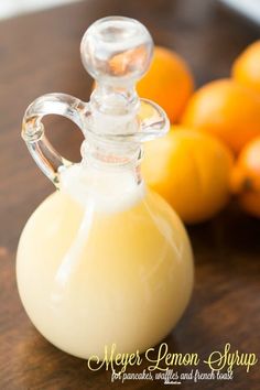 a glass bottle filled with liquid sitting on top of a table next to oranges