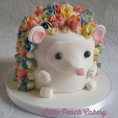 a white cake decorated with flowers and a hedge on it's head is sitting on a table