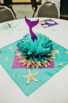 a table topped with a purple and blue centerpiece on top of a white table