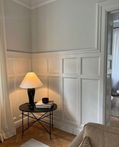 a table with a lamp on top of it next to a couch in a living room