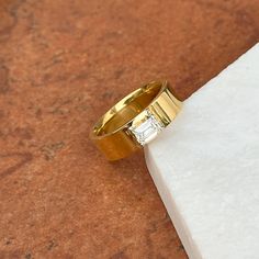 a gold ring with a single diamond on it sitting on a piece of white paper