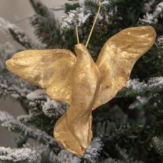 a gold angel ornament hanging from a christmas tree with snow on the branches