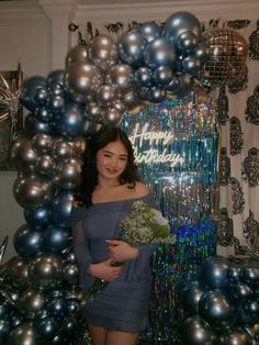 a woman is standing in front of balloons and holding a bunch of broccoli